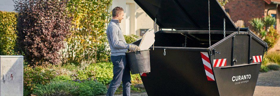 Person wirft Eimer in Container